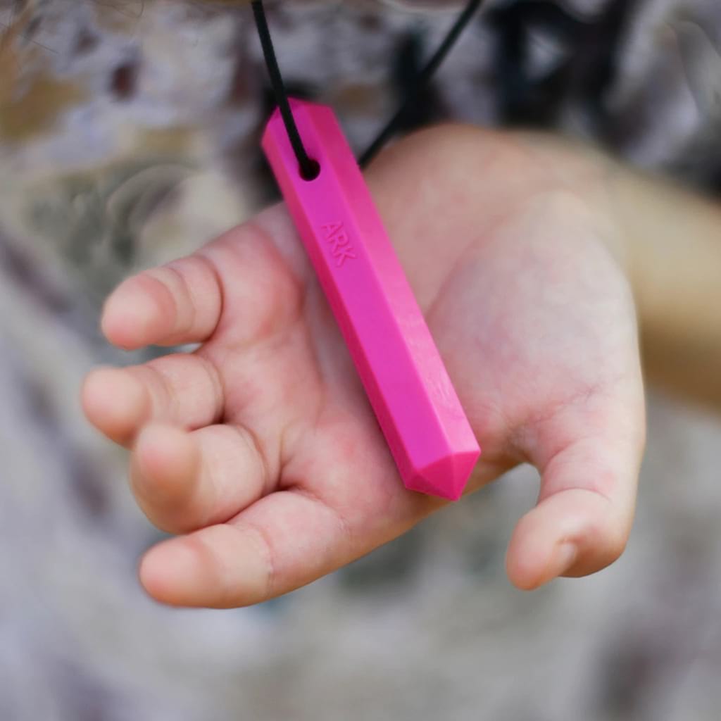 Child hand holding Ark's krypto bite chew necklace Australia in pink