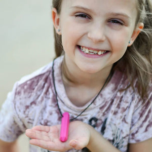Girl holding Ark's krypto bite chew necklace in pink 