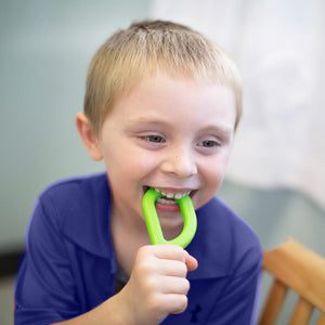 Caucasian boy chewing on Ark's original sensory chewy tool in lime green medium toughness