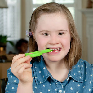 Caucasian girl with Down Syndrome chewing on Ark's original silicone chew toy in lime green medium toughness