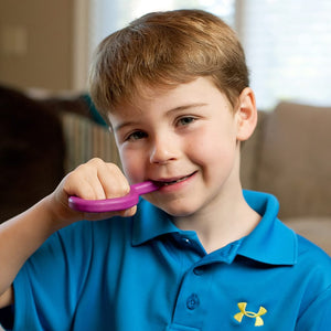 Caucasian boy chewing on Ark's original silicone sensory chew in magenta standard toughness