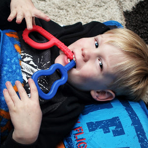 Caucasian boy chewing on Ark's  guitar shaped and textured grabber sensory toys Australia
