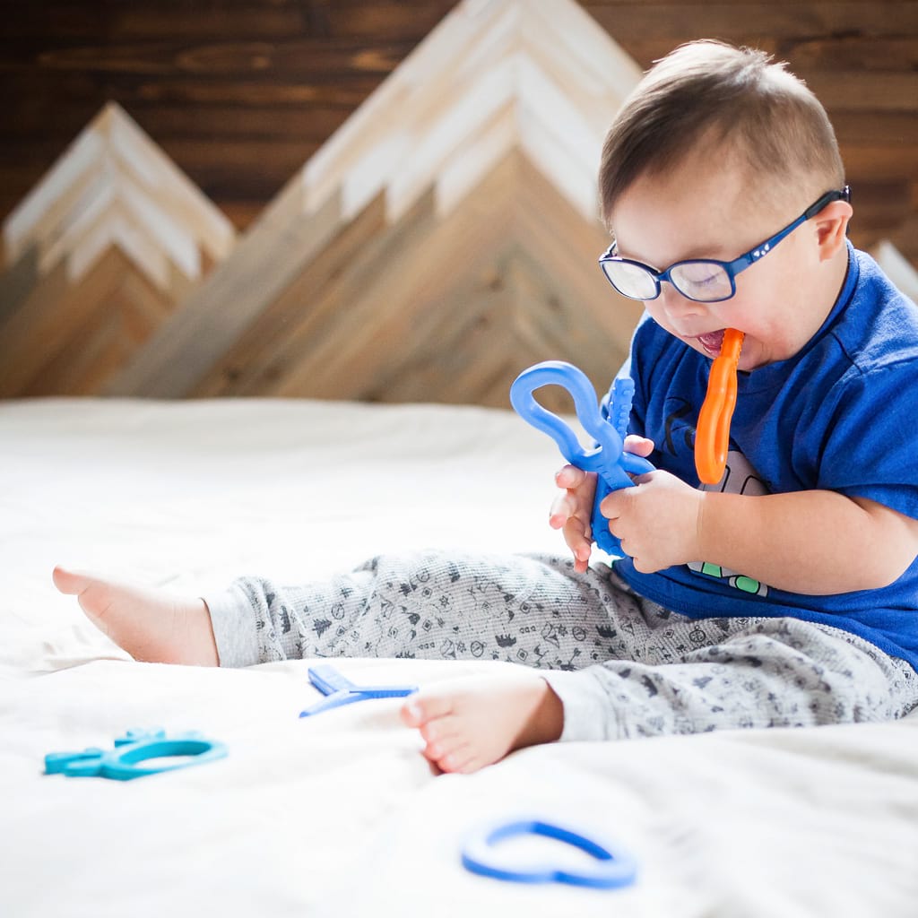 Autistic toddler chewing on Ark's guitar oral motor sensory chew toy