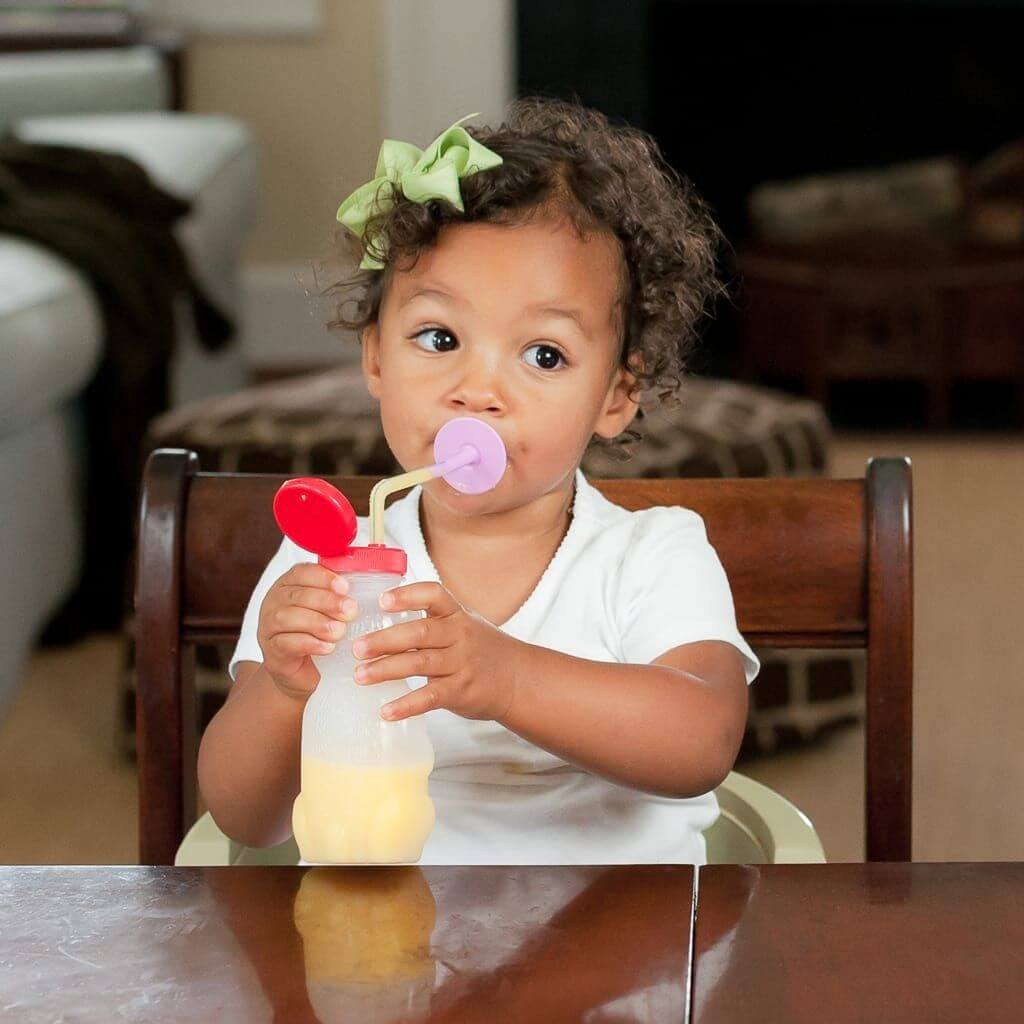 Afro american girl with ribbon in her hair drinking from honey bear straw cup Australia