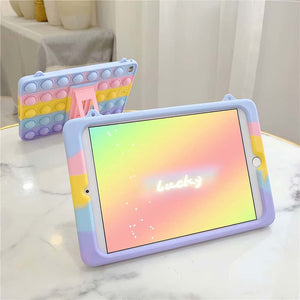 2 fidget popper iPad cases for kids in pastel colours on a marble table