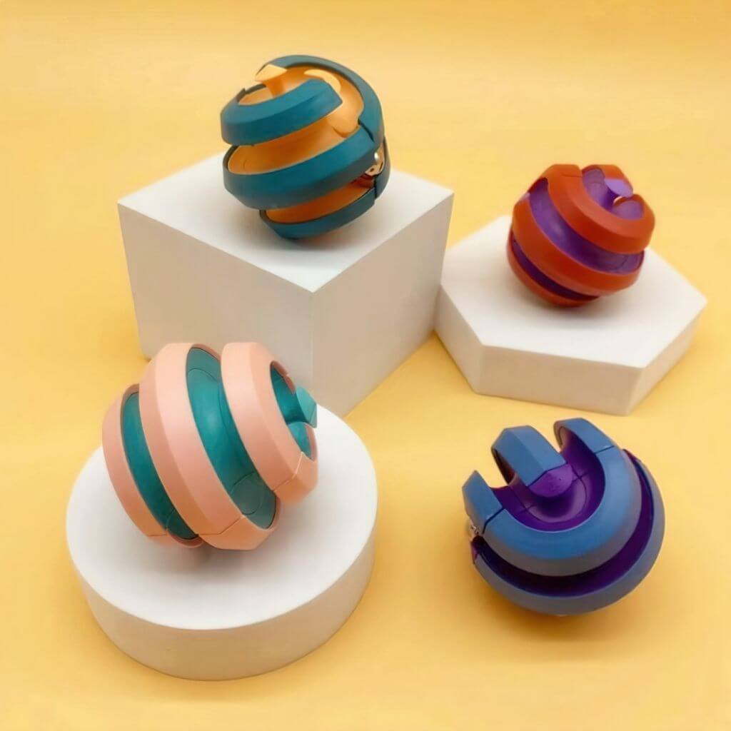 Orbital ball fidget toys red blue pink teal on yellow background