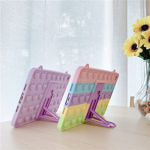 Pop it iPad cases on a table next to a window and a vase with flowers