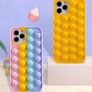 Pop bubble wrap phone case iPhone in rainbow colours next to an yellow iPhone case on a mauve background