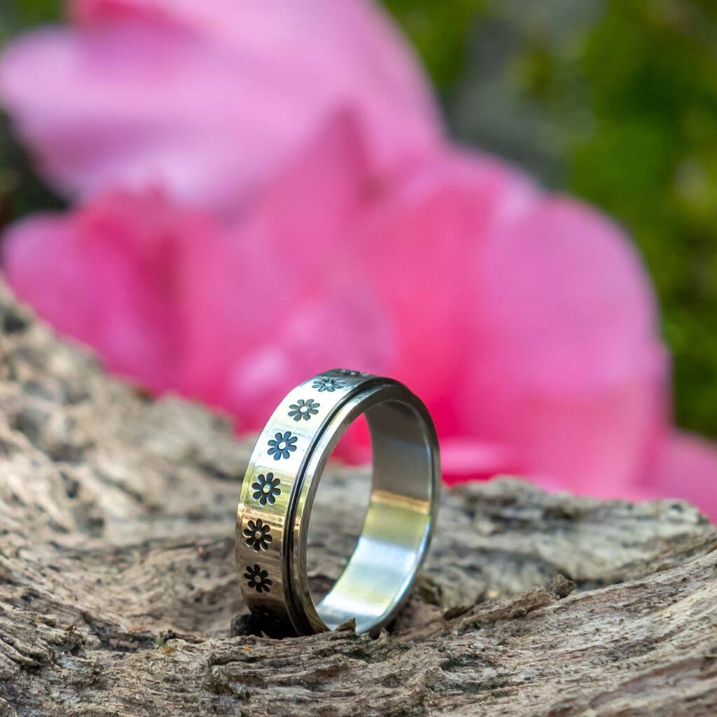 Stainless steel flowers fidget ring close up on a tree trunk