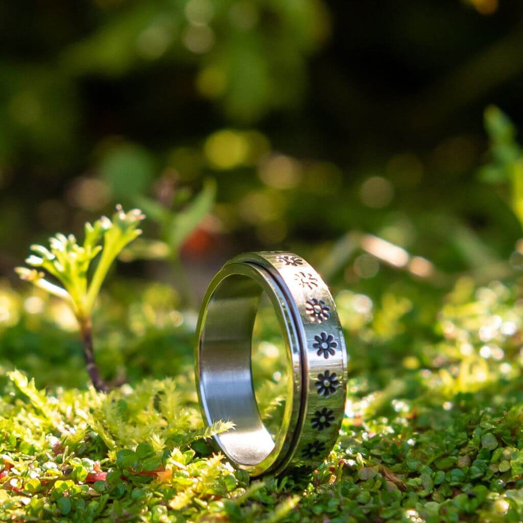 Stainless steel women's flowers spinner ring Australia on green moss background