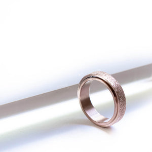 Rose gold stainless steel sparkly spinner ring on white background
