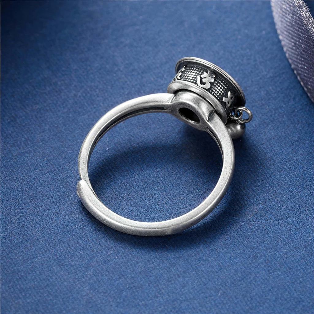 Sterling silver Buddhist Tibetan prayer wheel spinner ring on blue background