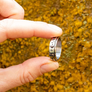 Sun moon and stars silver spiner ring close up on yellow moss background