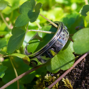 Sun moon and stars stainless steel spinner ring on green leaves close up