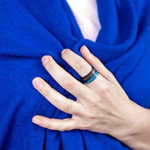 Woman holding blue shawl with hand wearing black and blue sparkly spinner rings Australia