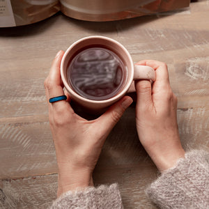 Woman holding tea mug with hand wearing a blue sparkly spinner ring
